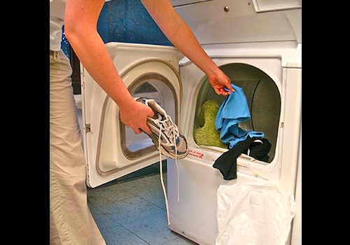 picture of a person putting clothes and shoes in a dryer