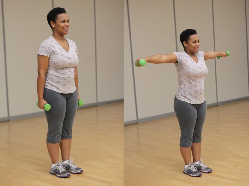 Woman standing with her arms down holding dumbells. Then she raised her arms by her sides to the shoulder height making a "T" shape with her body.
