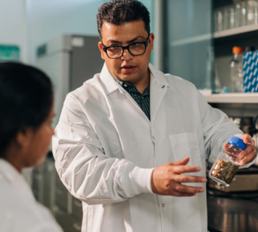 Photo of Reza wearing lab coat and holding a jar