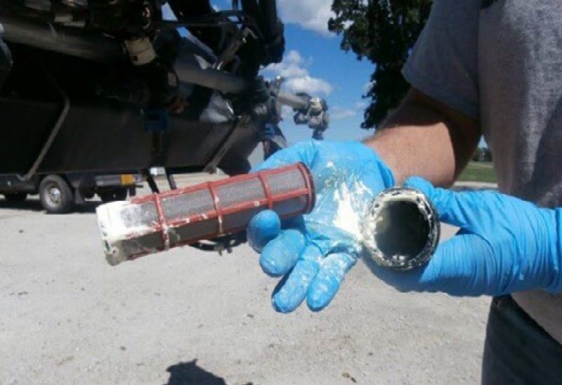 A man holding clogged filter due to un-dissolved pesticides
