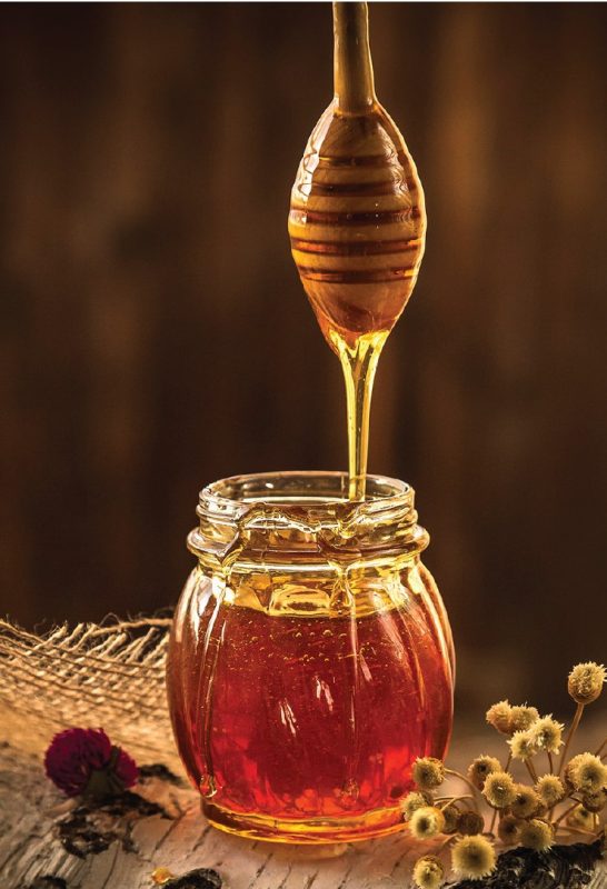 a photo of honey in a jar with a honey dipper