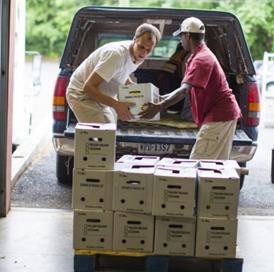 Photo of two people unloading boxes from a truck.