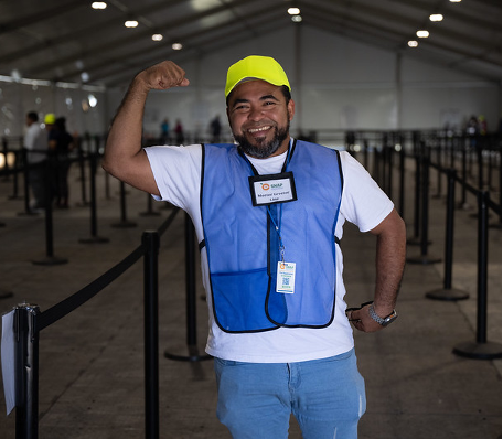 Man wearing a blue vest and a neon yellow hat.