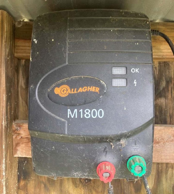 A Gallagher M1800 energizer attached to a wooden structure.