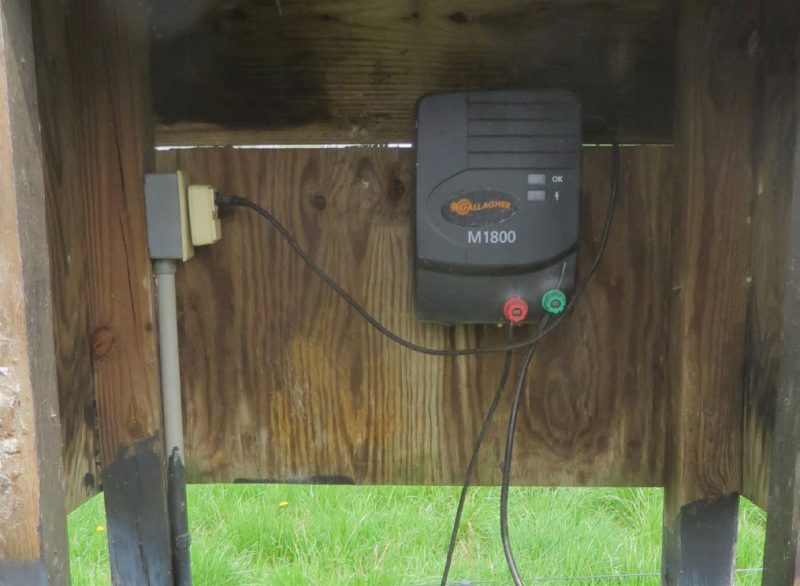 An energizer situated in a small shelter constructed with four-by-fours and what appears to be plywood.